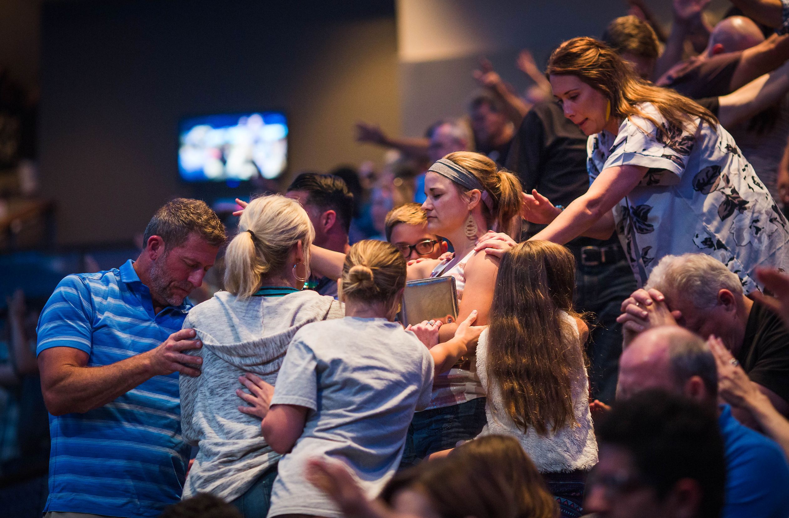 People standing around a woman in prayer